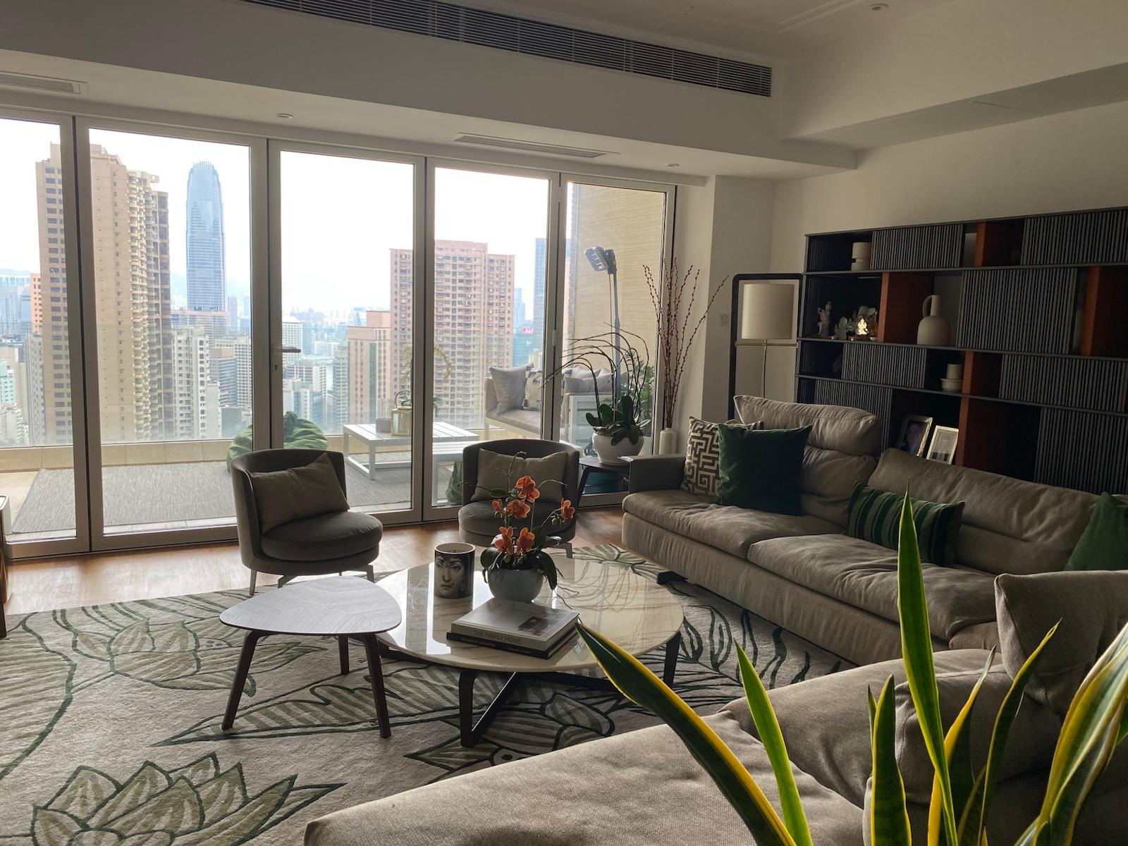 Living room and botanical rug overlooking balcony windows and the city skyline