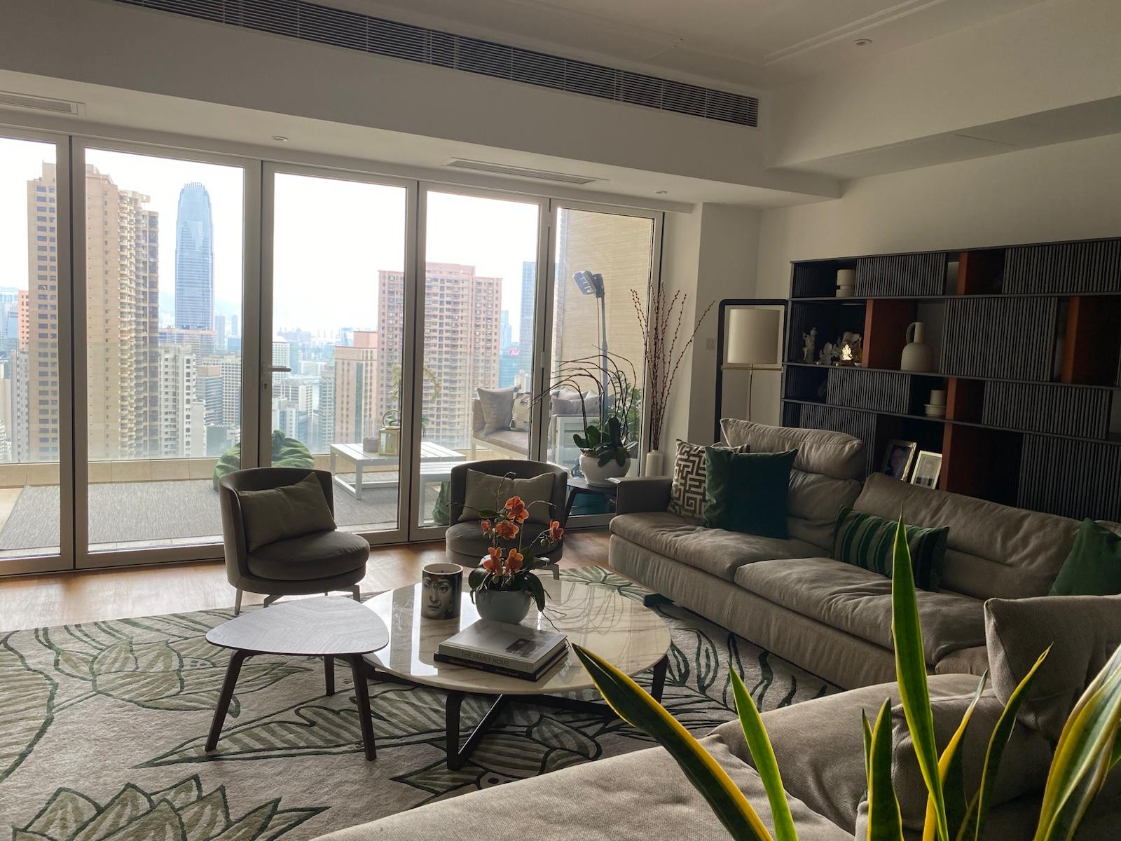 Green armchairs, curved coffee tables and beige sofa beside full-height windows