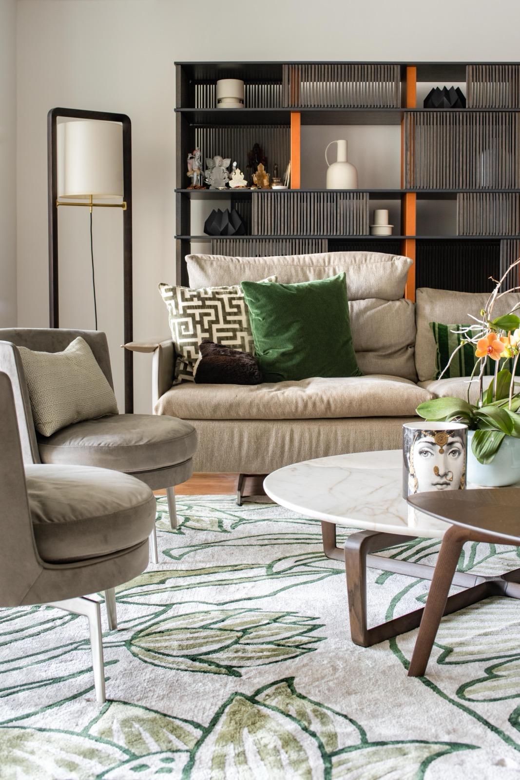 Green cushion and beige sofa beside a floor lamp, with botanical rug and coffee tables