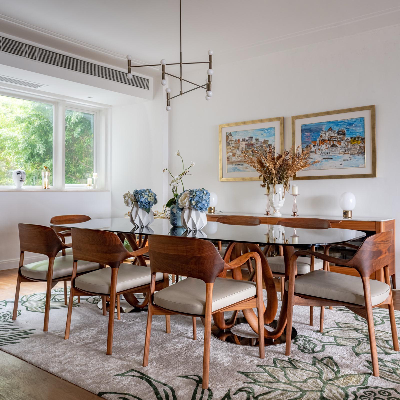 Timber dining table and chairs beside a window with blue floral arrangements