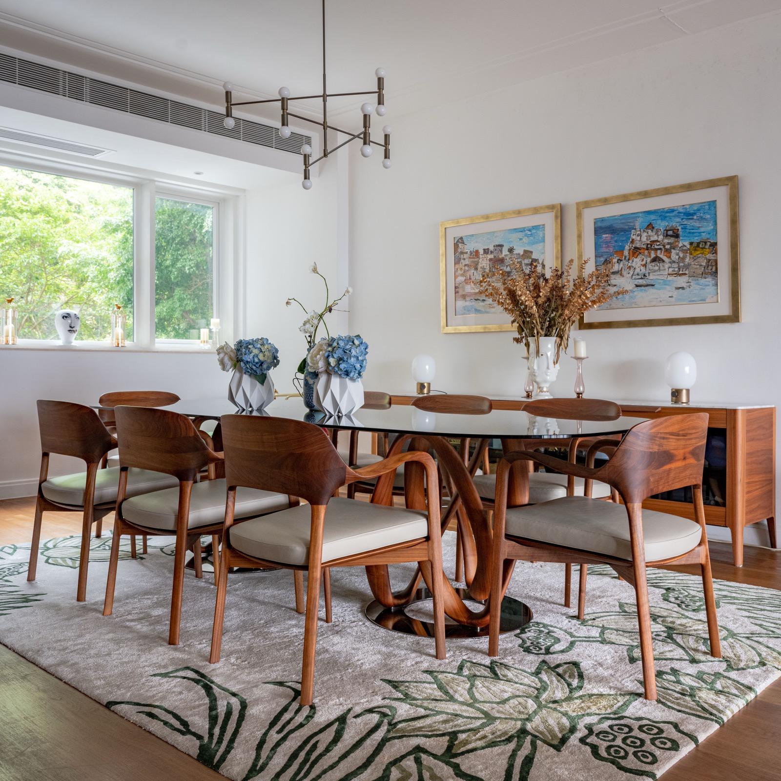 Dining area with timber chairs, blue flowers and framed artwork beside the window