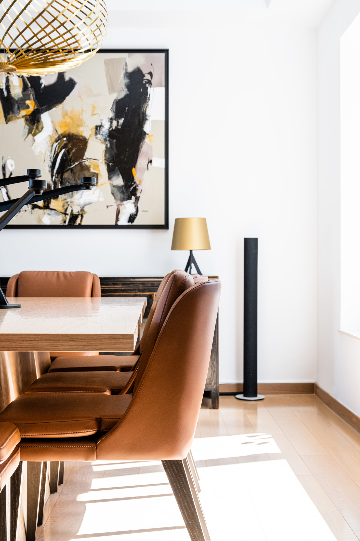 Rust dining chair and timber table detail with abstract artwork and a pendant light