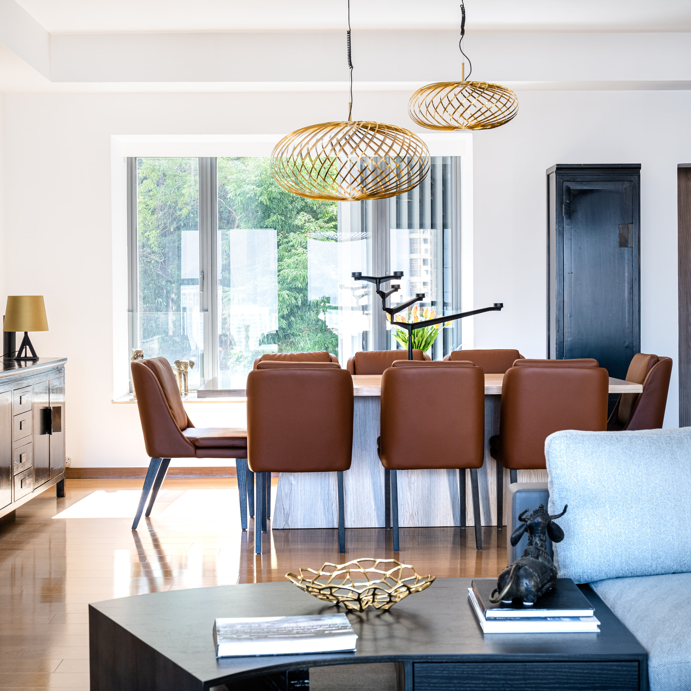 Dining table and rust upholstered chairs beneath two woven pendant lights