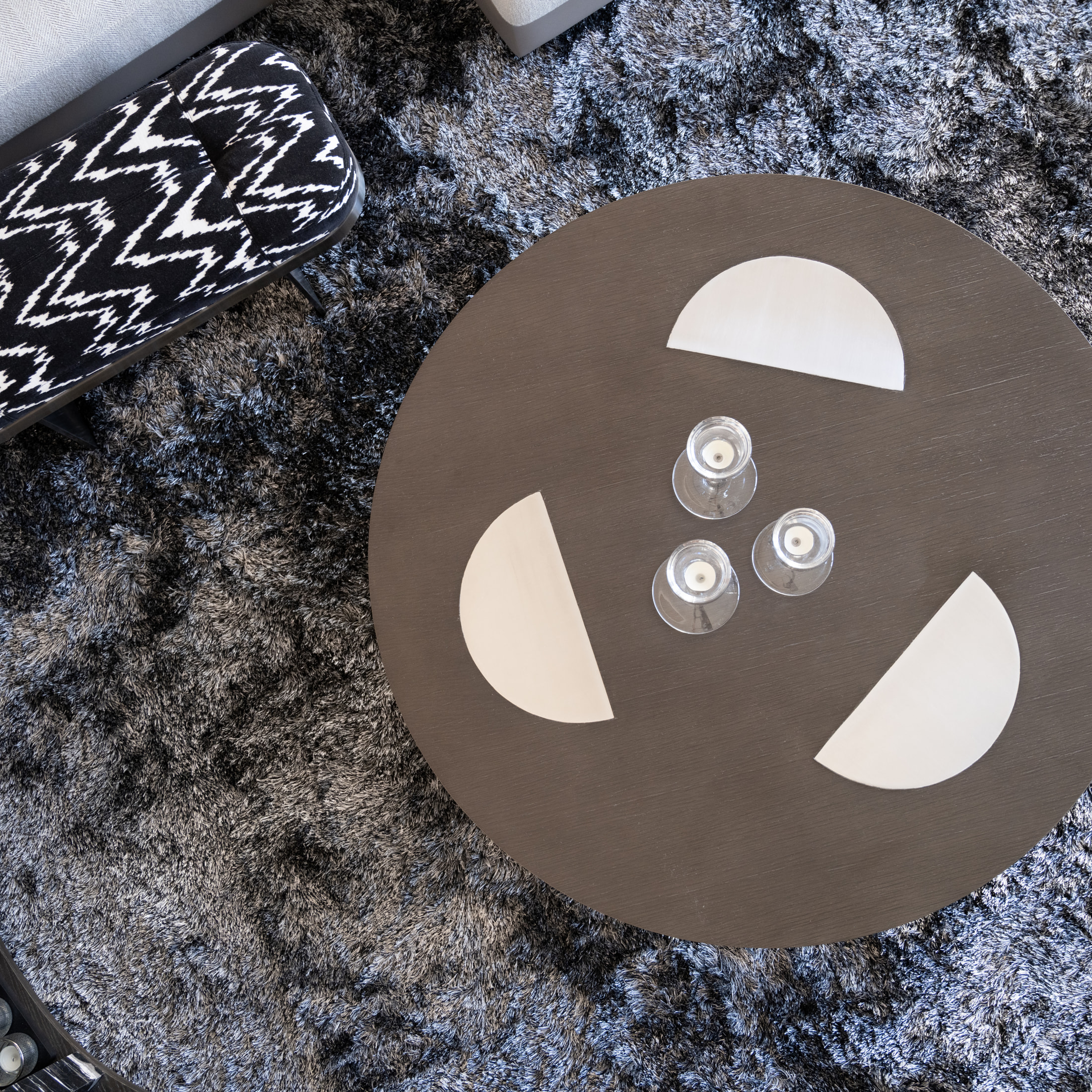 Overhead detail of the oval coffee table and patterned upholstered bench on a textured rug
