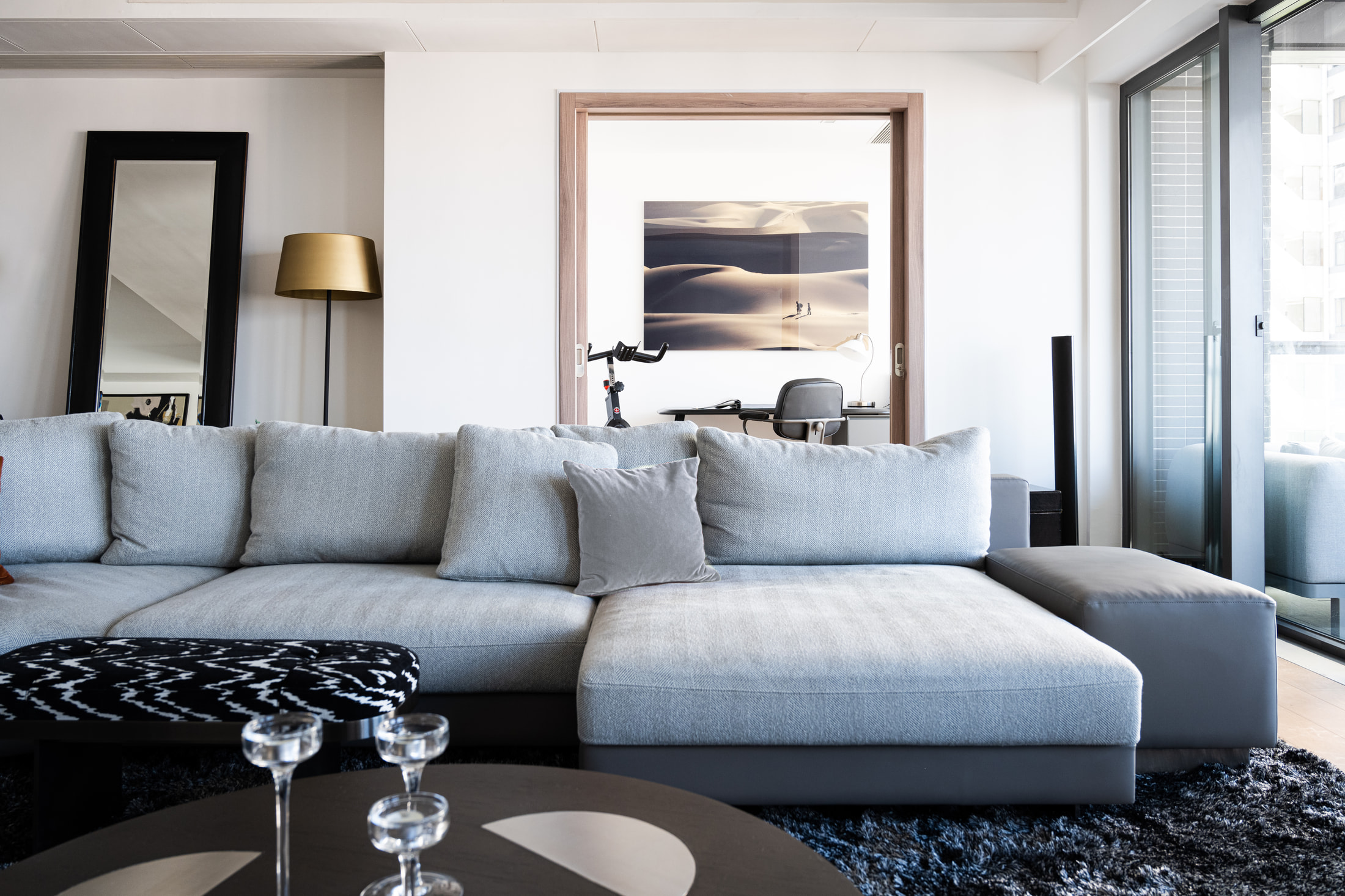 Sectional chaise, patterned upholstered bench and an art-filled home office doorway